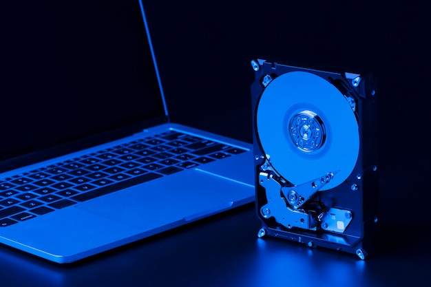 Free photo hard drive with blue light and laptop high angle