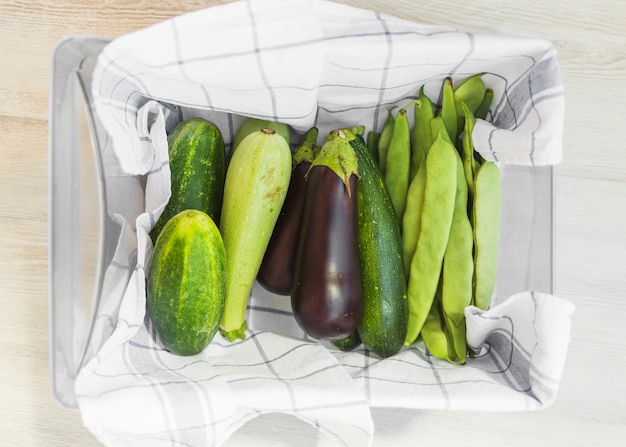 Free photo harvested fresh vegetables in the container with napkin