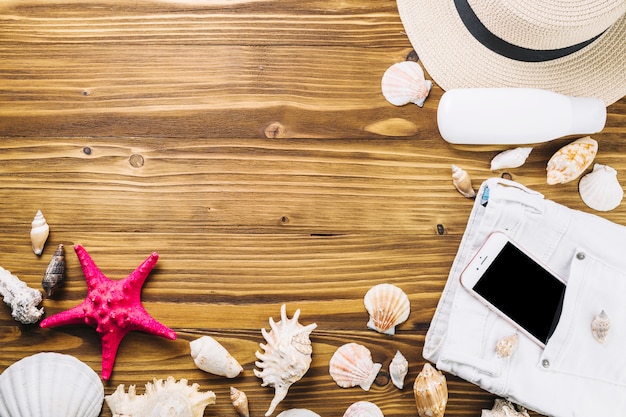 Hat and smartphone near seashells and starfish