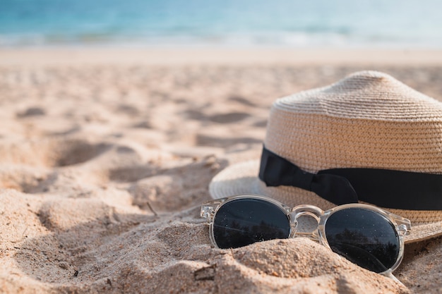 Free photo hat with sunglasses on sand