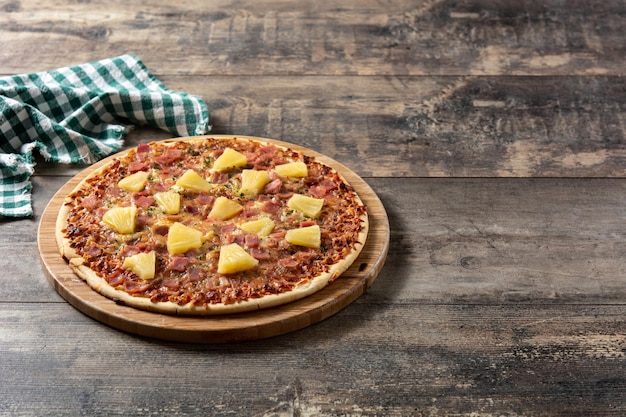 Hawaiian pizza with pineappleham and cheese on wooden table