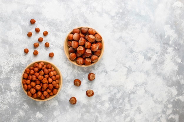 Hazelnut with peeled hazelnuts in small plate on concrete , top view.