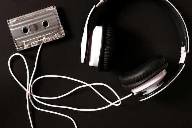 Headphone connected to transparent cassette on black background