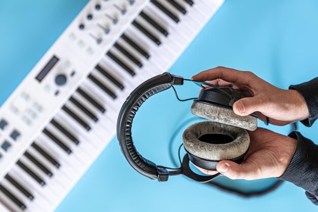 Headphones in male hands against the background of musical keys top view