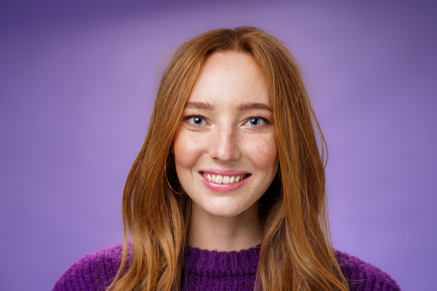 Free Photo headshot of charming attractive and happy young redhead woman with freckles and bright white smile, grinning satisfied at camera as posing over purple background friendly and delighted.