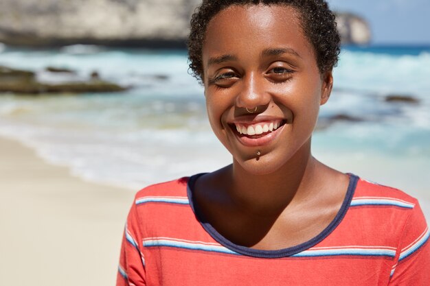 Headshot of pleasant looking cheerful black young woman with boyish appearance