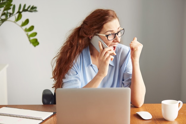 Headshot of a successful businesswoman looking excited talking on the cell phone