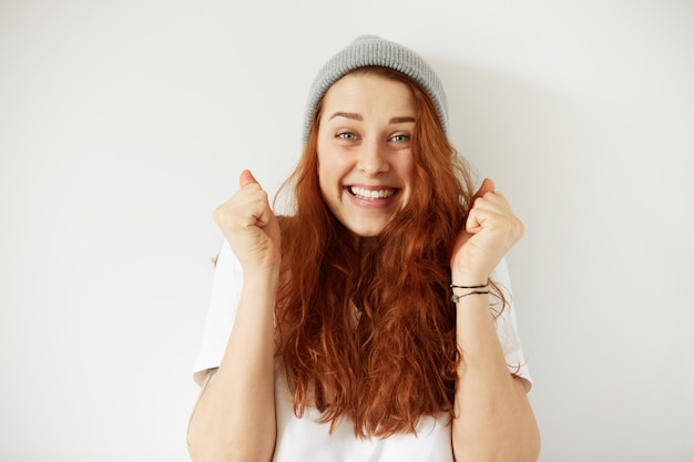 Headshot of young happy female wearing gray cap and T-shirt with joyful winning smile