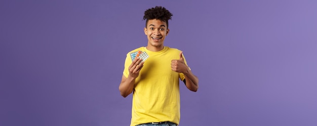 Health influenza covid concept portrait of young healthy man got better show thumbsup holding drugs