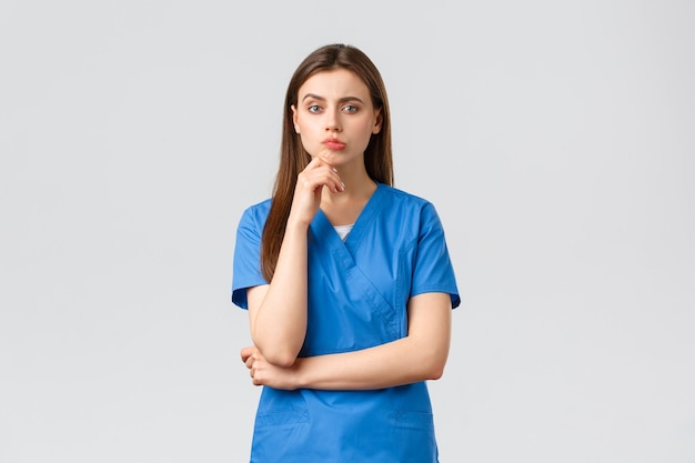 Healthcare workers, prevent virus, insurance and medicine concept. Troubled thoughtful female nurse or doctor trying find answer question, raise finger up in eureka, have idea, suggest plan