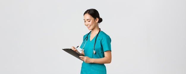 Free Photo healthcare workers, preventing virus, quarantine campaign concept. beautiful smiling asian doctor, nurse running checkup in hospital, looking at clipboard with patient results, examine people.