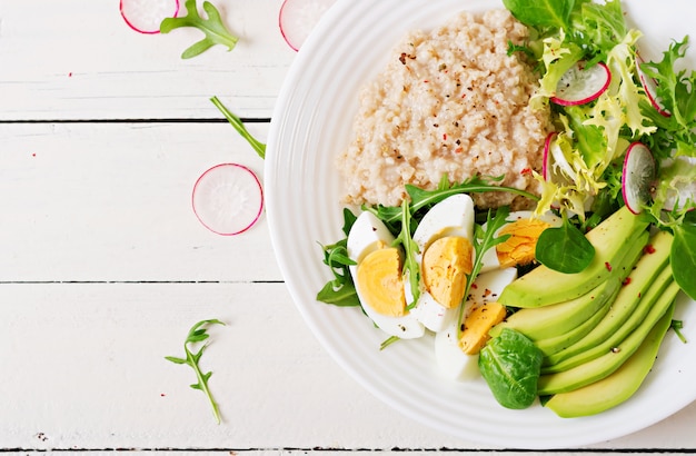 Free photo healthy breakfast. dietary menu. oatmeal porridge and avocado salad and eggs. top view