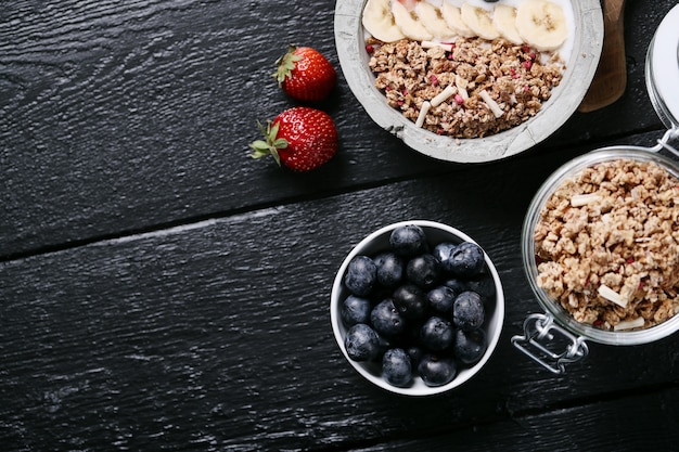 Healthy breakfast with cereals and fruits on black wooden table