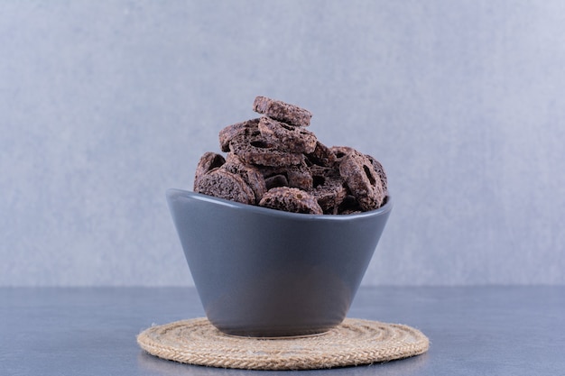 Healthy breakfast with chocolate corn rings in a black bowl on a stone.