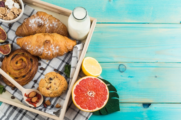 Healthy breakfast with croissant; backed cookies; milk; muesli; and citrus fruit on wooden tray