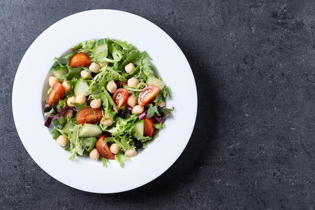 Free photo healthy chickpea salad with tomatolettuce and cucumber on black slate background