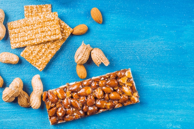 Healthy dried fruits bar with almonds and peanuts on blue background