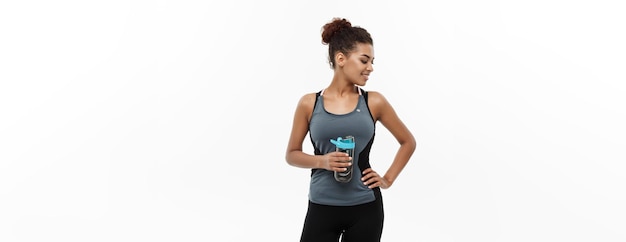 Healthy and Fitness concept beautiful African American girl in sport clothes holding water bottle after workout Isolated on white studio background