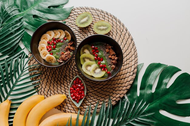 Healthy food concept. Top view on table with smoothie bowls.  Plate topped with kiwi, granola, garnet, chia, avocado.