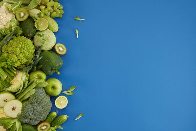 Free photo healthy food dish on blue background. healthful set including vegetables and fruits. grape, apple, kiwi, pepper, lime, cabbage, zucchini, grapefruit. proper nutrition or vegetarian menu.