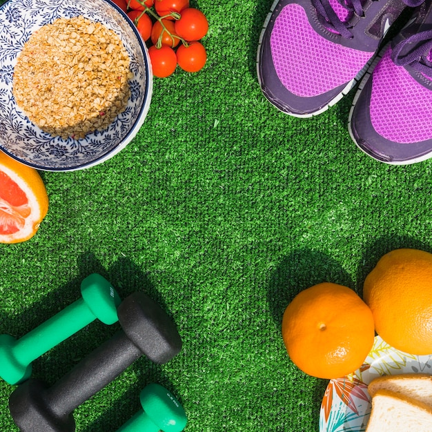 Free photo healthy food with pair of sport shoes and dumbbells on turf