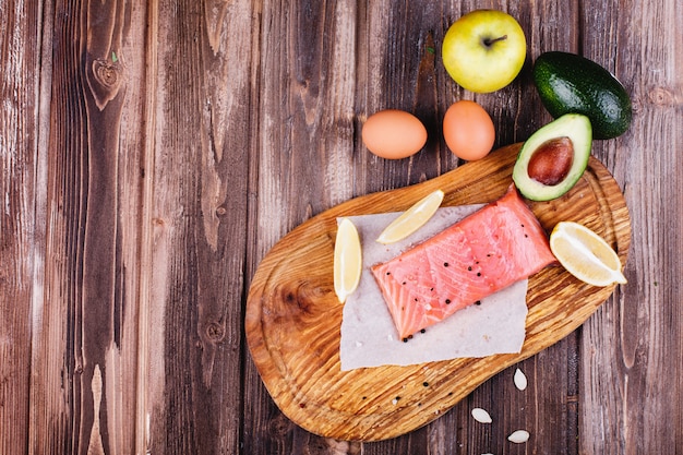 Healthy and fresh food. Raw salmon served with lemons, eggs, apples, avocado and knives