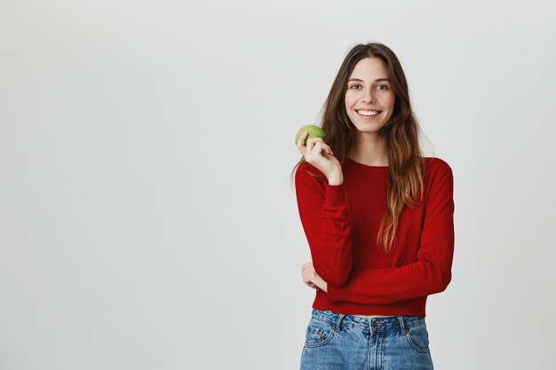 Healthy lifestyle and sport concept. Smiling attractive woman eating apple