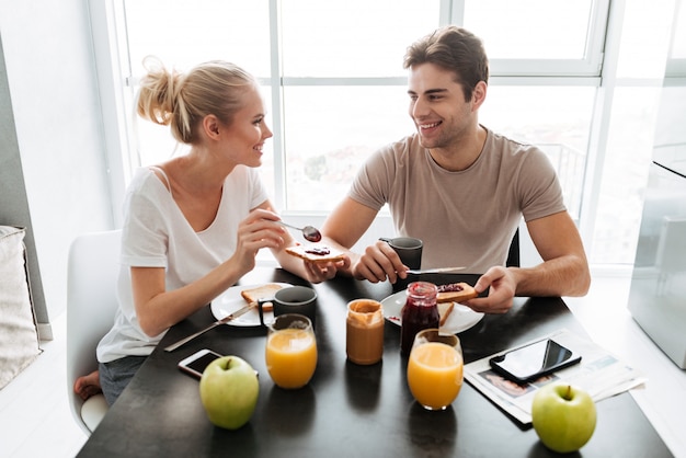 Healthy lovers sitting in kitchen and eating breakfast