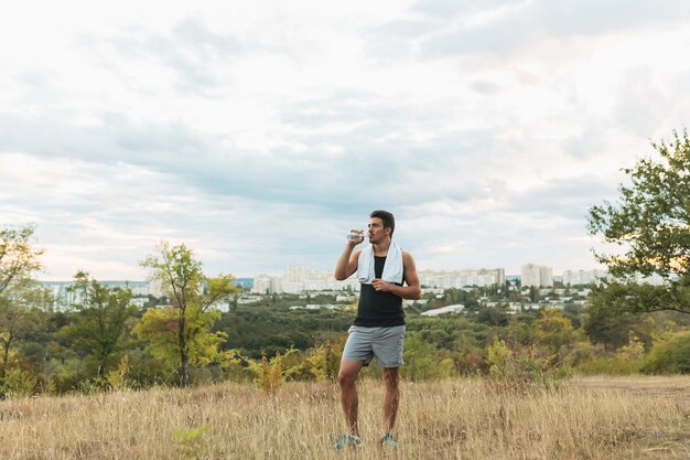 Healthy man drinking water on nature while resting