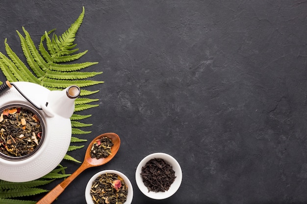 Free photo healthy organic tea with dry herb and fern leaves on black surface