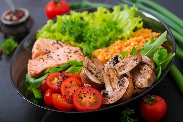 Free photo healthy salad with salmon, tomatoes, mushrooms, lettuce and lentil on dark