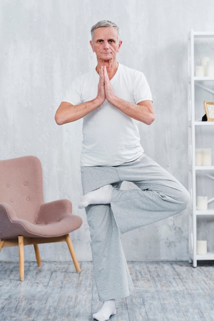 Free photo healthy senior man practicing yoga looking at camera