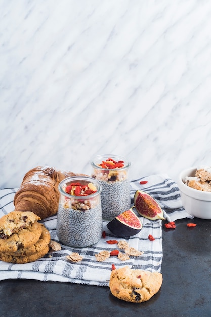 Free Photo healthy smoothie with backed cookies and croissant on napkin against marble textured background