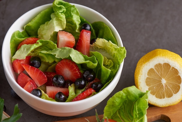 Healthy strawberries salad with butterhead, blackberry in a white plate.