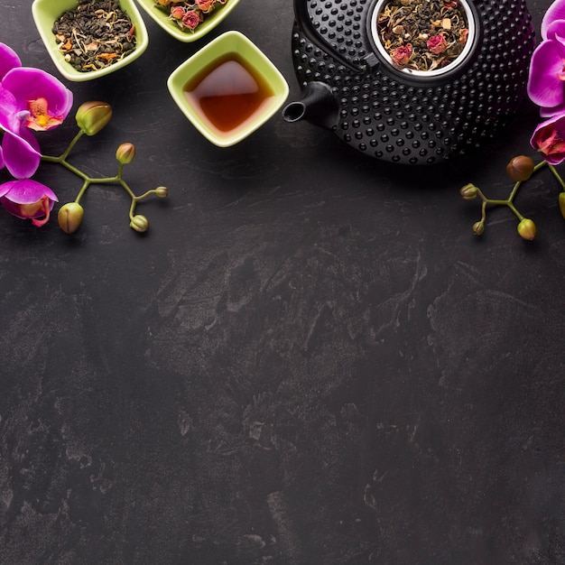 Free Photo healthy tea with dried ingredient and pink orchid flower on black background