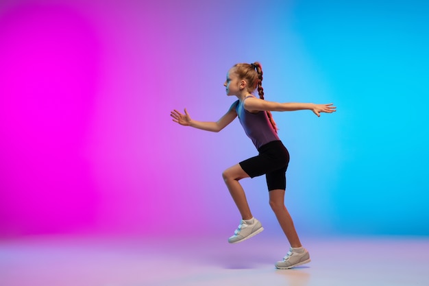 Healthy. Teenage girl, professional runner, jogger in action, motion isolated on gradient pink-blue background in neon light. Concept of sport, movement, energy and dynamic, healthy lifestyle.