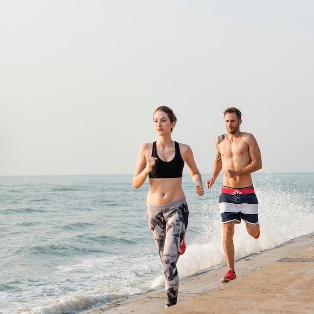 Free photo healthy young couple running by the beach