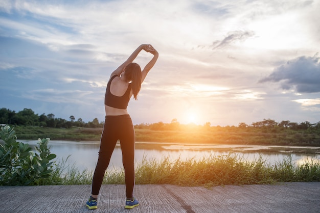 Healthy young woman warming up outdoors workout before training session at the park.