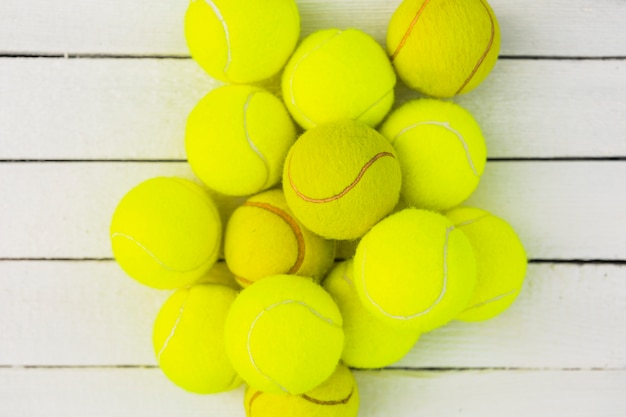 Free photo heap of green tennis balls on wooden table