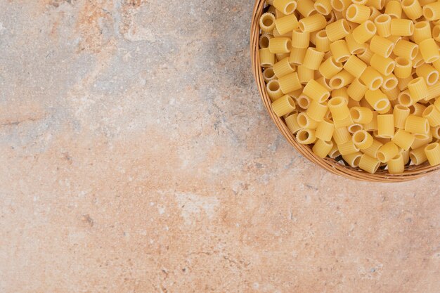 Free photo heap of raw ditalini pasta on wooden basket.