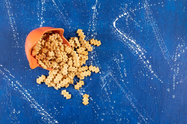 Free photo heap of salty small crackers placed out of orange bowl