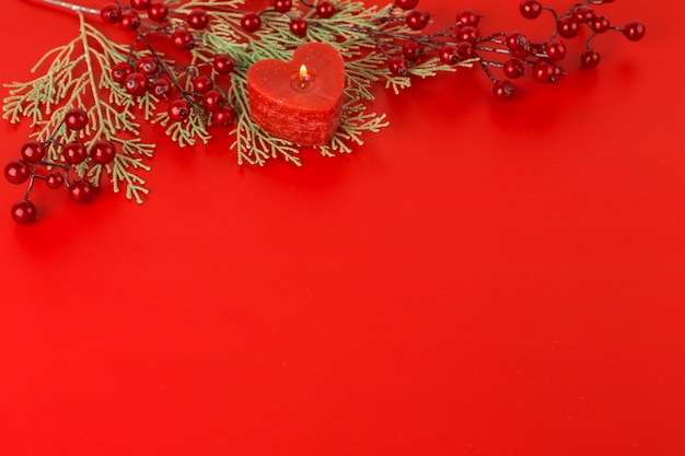 Heart candle with red berries on table