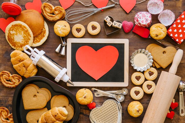 Free photo heart and chalkboard near bakeware and pastry