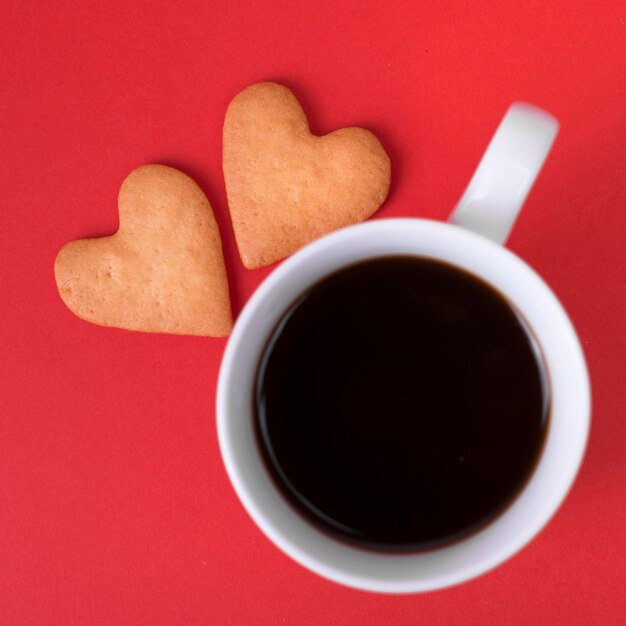 Heart cookies with coffee cup on red table