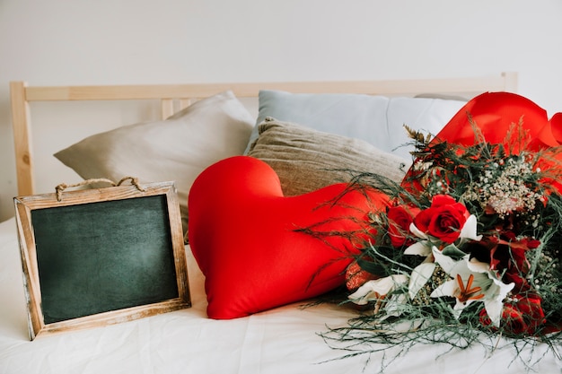 Free photo heart cushion between blackboard and bouquet