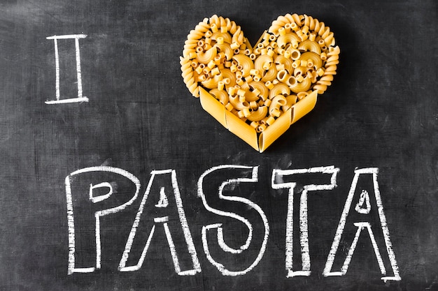 Free photo heart made with different type of pasta and text on blackboard