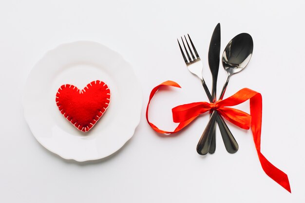 Heart on plate near utensils