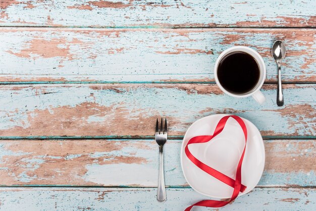 Heart shape from ribbon on plate with coffee 