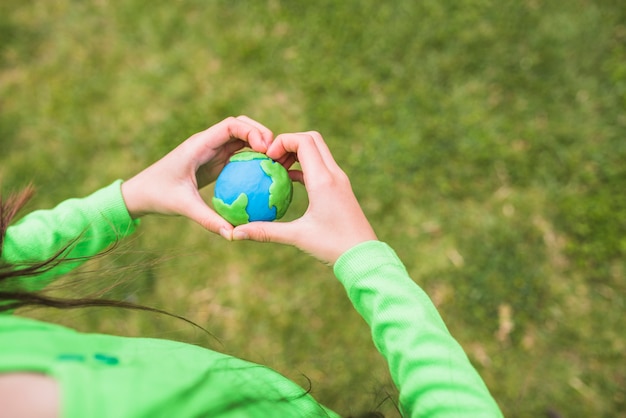 Free photo heart shape hands surrounds the colorful plasticine planet