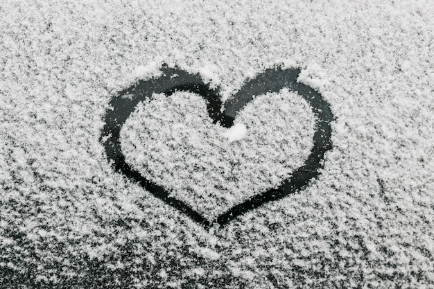 Heart shape on snowy glass during winter day